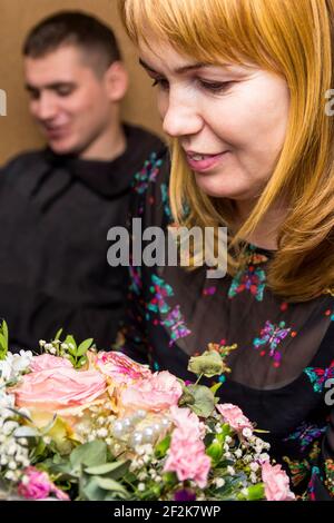 Fête des mères. Une femme admire un magnifique bouquet de son fils. La blonde regarde l'arrangement de fleur. Félicitations pour la Journée des femmes, la Fête des mères Banque D'Images