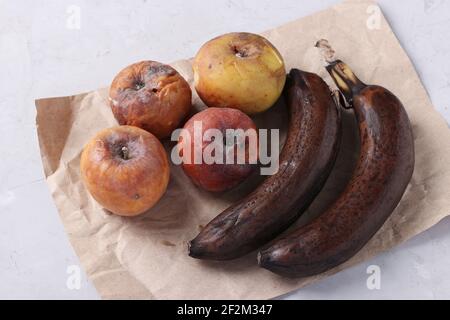 Aliments pourris gâtés avec moisissures : pommes et bananes sur fond gris. Gros plan. Banque D'Images