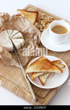 Petit déjeuner délicieux, table de brunch. Café, pain grillé frais, camembert au fromage, noix de cajou sur planche en bois. Banque D'Images