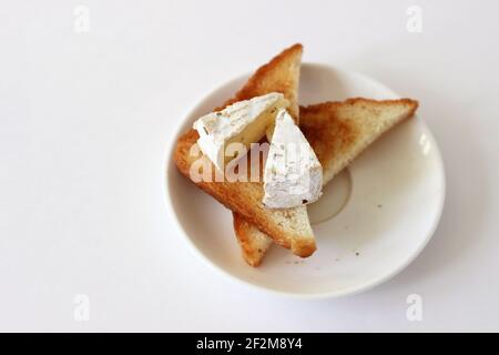 Camembert au fromage sur des toasts croquants frais isolés sur la table blanche. Banque D'Images