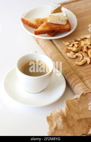 Café du matin servi avec des toasts avec du fromage à la brie et des noix de cajou sur une planche à bois. Petit déjeuner à la maison. Banque D'Images