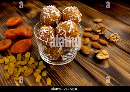 Boules d'énergie avec des abricots séchés et des ingrédients dans le verre plaque sur fond de bois marron Banque D'Images