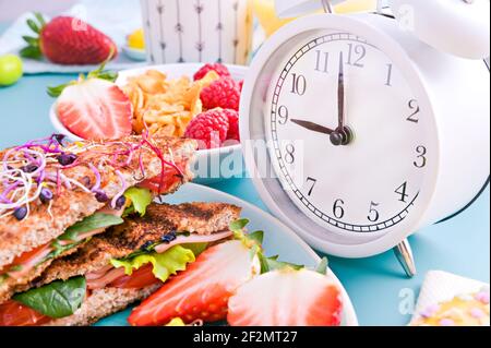 Super nourriture pour le petit déjeuner. Pain grillé au jambon, salade et brouille, parsemé de graines germées, une assiette de céréales avec baies, super nourriture. Délicieux petit déjeuner sain sur fond lumineux Banque D'Images