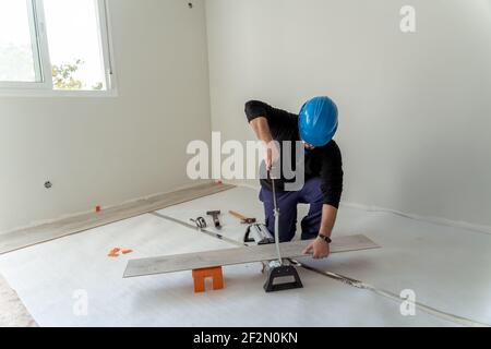 menuisier coupant une feuille de bois pour installer le plancher dans une rénovation de maison Banque D'Images