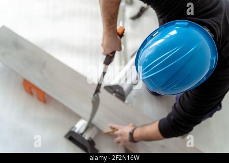 Vue aérienne d'un charpentier coupant un stratifié de bois à installer un plancher en bois Banque D'Images