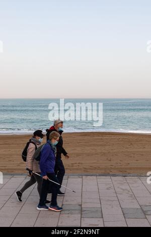 Trois personnes marchant le long du front de mer à Biarritz avec des masques chirurgicaux. Banque D'Images