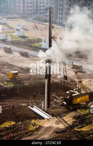 Pilotant les piles de fondation d'un bâtiment à plusieurs étages. Le conducteur de pieu pousse des piles dans le sol pour la fondation de la maison Banque D'Images