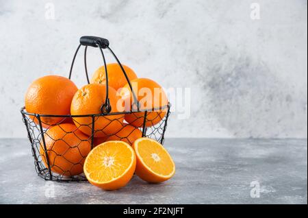 Un panier noir métallique rempli de fruits orange juteux arrière-plan en pierre Banque D'Images