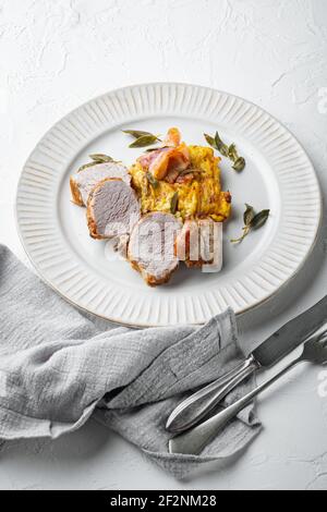 Filet de porc grillé et gratin de pommes de terre avec sauge et prosciutto, sur plat, sur fond de pierre blanche Banque D'Images