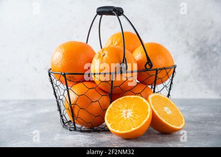 Un panier noir métallique rempli de fruits orange juteux arrière-plan en pierre Banque D'Images