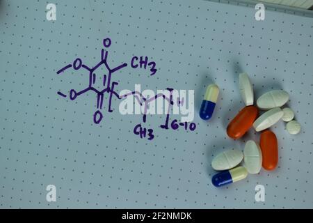 Vitamine Coenzyme Q10 avec formule chimique écrire sur un livre isolé sur une table en bois. Banque D'Images