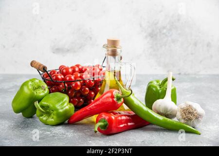 Tomates cerises dans un panier avec piments, ail et huile d'olive Banque D'Images