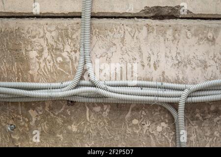 Tubes en aluminium pour la protection des fils alignés sur le béton ancien mur Banque D'Images