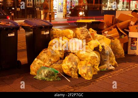 Sacs jaunes et poubelles debout dans la rue au crépuscule, Brême, Allemagne Banque D'Images