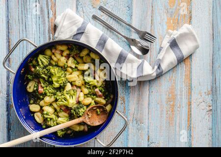 Vue de dessus sur le brocoli frais préparé avec gnocchi en cocotte plat sur la table en bois - nourriture saine maison dans lumière vive avec espace de copie Banque D'Images