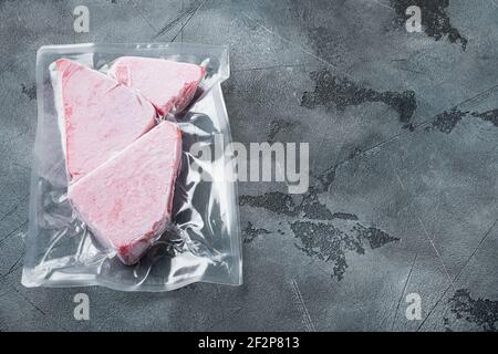 Ensemble sous vide de steak de thon congelé, sur fond de pierre grise , avec espace de copie et espace pour le texte Banque D'Images