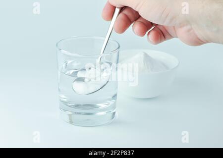 Bicarbonate de soude dans un verre d'eau. Cuillère de bicarbonate de soude et verre d'eau. Bicarbonate de soude, bicarbonate de soude, bicarbonate de soude. Banque D'Images