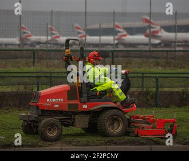 Londres, Heathrow Airport - Mars, 2020: Avec la majorité des avions garés en raison du coronavirus, un travailleur isolé entretient le sol de l'aéroport. Photographe Banque D'Images