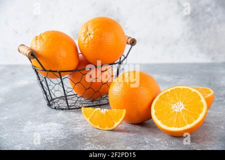Un panier noir métallique rempli de fruits orange juteux arrière-plan en pierre Banque D'Images