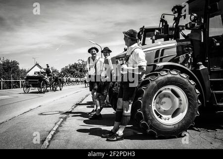 Allemagne, Bavière, Antdorf, semaine de fête de l'association traditionnelle de costumes. Des hommes habillée de tradition regardent le défilé de calèche sur les tracteurs. Banque D'Images