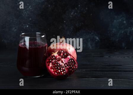 Un verre de jus de grenade sur fond sombre Banque D'Images