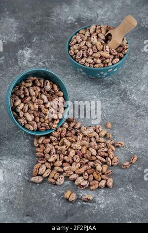 Grains de haricots crus affichés dans des bols sur une surface en marbre Banque D'Images