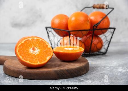 Un panier noir métallique rempli de fruits orange juteux arrière-plan en pierre Banque D'Images