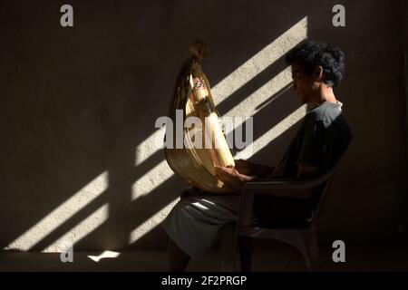 Hance PAH posant pour une photo avec un sasando électrique, l'instrument de musique à cordes traditionnel de l'île de Rote qu'il a créé, dans sa maison dans le village de Lalu Koen, île de Rote, est Nusa Tenggara, Indonésie. Banque D'Images