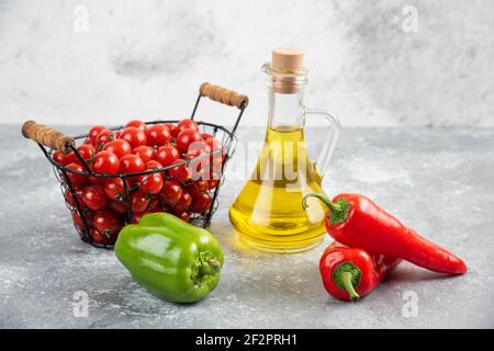 Tomates cerises dans un panier avec piments et huile d'olive Banque D'Images