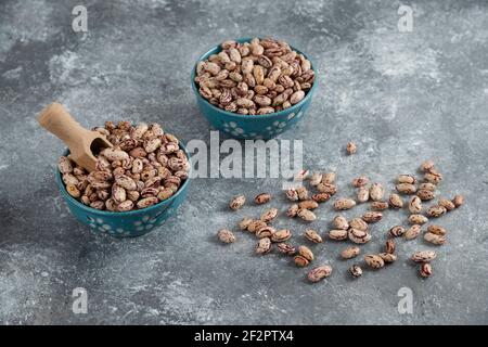 Grains de haricots crus affichés dans des bols sur une surface en marbre Banque D'Images