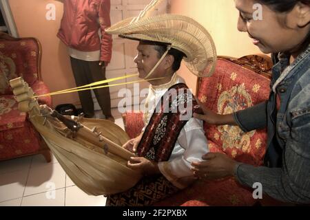 Vêtu de la tenue traditionnelle de l'île de Rote, Yusuf Messah joue une chanson traditionnelle avec un instrument sasando dans sa maison du village de Meoain à l'île de Rote, à l'est de Nusa Tenggara, en Indonésie. « il y a encore des gens qui font et jouent au sasando », dit-il, « cet instrument est toujours vivant dans notre communauté ». Banque D'Images