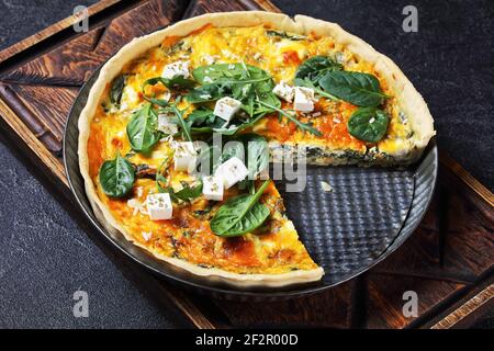 feta épinards cheddar quiche dans un plat de cuisson sur une planche en bois sur une table en béton gris, cuisine française Banque D'Images