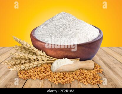 Farine de blé dans un bol et épillets isolés sur fond en bois Banque D'Images