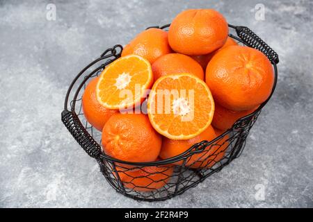 Un panier noir métallique rempli de fruits orange juteux arrière-plan en pierre Banque D'Images