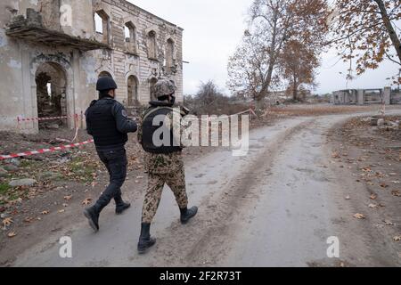 AGDAM, AZERBAÏDJAN - DÉCEMBRE 14 : des militaires azerbaïdjanais se promèrant dans des bâtiments en ruines de la ville d'Agdam qui a été détruite par les forces arméniennes lors de la première guerre du Haut-Karabakh le 14 décembre 2020 à Agdam, en Azerbaïdjan. La ville et son district avoisinant ont été retournés sous contrôle azerbaïdjanais dans le cadre d'un accord qui a mis fin à la guerre du Haut-Karabakh de 2020. Banque D'Images