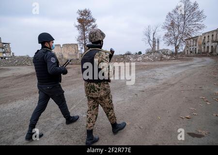 AGDAM, AZERBAÏDJAN - DÉCEMBRE 14 : des militaires azerbaïdjanais se promèrant dans des bâtiments en ruines de la ville d'Agdam qui a été détruite par les forces arméniennes lors de la première guerre du Haut-Karabakh le 14 décembre 2020 à Agdam, en Azerbaïdjan. La ville et son district avoisinant ont été retournés sous contrôle azerbaïdjanais dans le cadre d'un accord qui a mis fin à la guerre du Haut-Karabakh de 2020. Banque D'Images