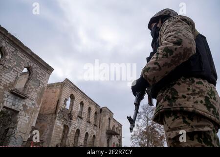 AGDAM, AZERBAÏDJAN - DÉCEMBRE 14 : un soldat azerbaïdjanais s'est intéressé à un bâtiment en ruines dans la ville d'Agdam qui a été détruit par les forces arméniennes pendant la première guerre du Haut-Karabakh le 14 décembre 2020 à Agdam, en Azerbaïdjan. La ville et son district avoisinant ont été retournés sous contrôle azerbaïdjanais dans le cadre d'un accord qui a mis fin à la guerre du Haut-Karabakh de 2020. Banque D'Images