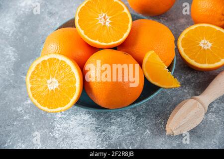 Un bol rempli de fruits d'orange émincés et entiers juteux avec alésoir en bois Banque D'Images