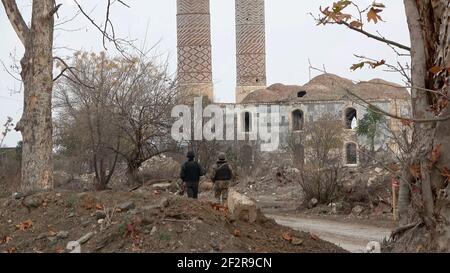 AGDAM, AZERBAÏDJAN - DÉCEMBRE 14 : des militaires azerbaïdjanais se promèrant dans des bâtiments en ruines de la ville d'Agdam qui a été détruite par les forces arméniennes lors de la première guerre du Haut-Karabakh le 14 décembre 2020 à Agdam, en Azerbaïdjan. La ville et son district avoisinant ont été retournés sous contrôle azerbaïdjanais dans le cadre d'un accord qui a mis fin à la guerre du Haut-Karabakh de 2020. Banque D'Images