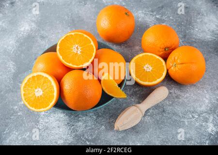 Un bol rempli de fruits d'orange émincés et entiers juteux avec alésoir en bois Banque D'Images