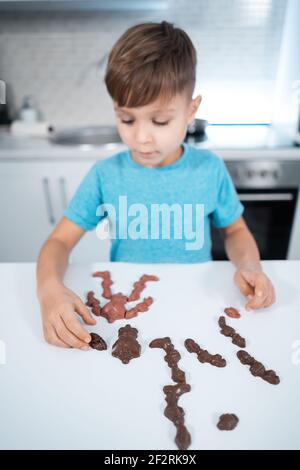 les enfants jouent avec des bonbons au chocolat ou des bonbons sur la table à la cuisine moderne Banque D'Images