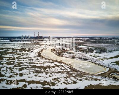 Vue aérienne de la centrale électrique à la lumière du soir. Paysage industriel urbain du début du printemps. Fonte de neige, changement de saison. Centrale à gaz près de la grande ville min Banque D'Images