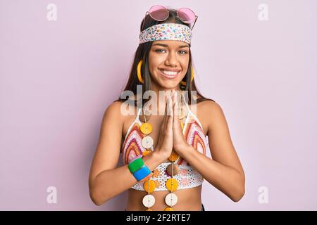Belle femme hispanique portant le style bohème et hippie priant avec les mains ensemble demandant pardon souriant confiant. Banque D'Images