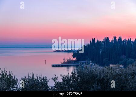 Magnifique coucher de soleil rose sur le lac de Garde. Vue sur le remblai et les jetées de la ville de Sirmione. L'hiver sur les lacs de l'Italie. Banque D'Images