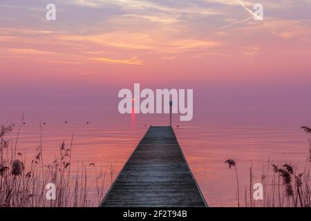 Magnifique coucher de soleil violet pendant le brouillard sur le lac de Garde, en Italie. Paysage de Moody. Banque D'Images