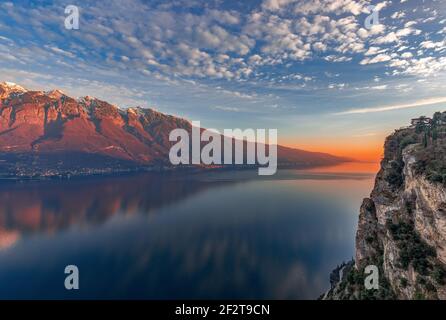 Superbe coucher de soleil sur le lac de Garde. Vue sur les Alpes enneigées peintes par le soleil couchant depuis la falaise de la ville de Tresmosine. Période d'hiver. Lombardie, Italie Banque D'Images