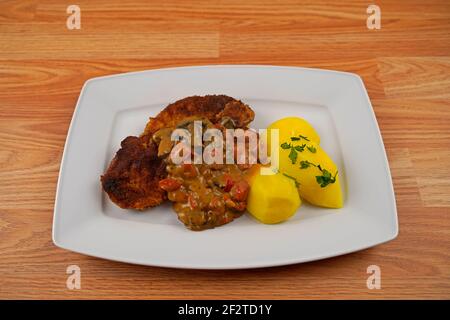 porc pané aux pommes de terre et aux champignons, sauce paprika sur une assiette de service blanche Banque D'Images