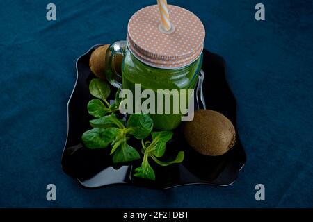 Smoothie aux feuilles de saladet au kiwi sur une assiette noire et décorée avec kiwi et laitue Banque D'Images