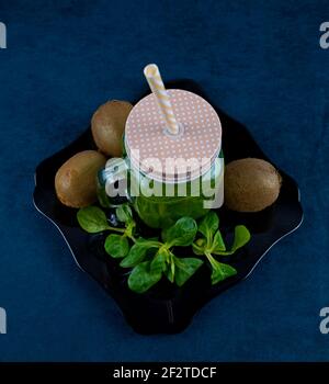 Smoothie aux feuilles de saladet au kiwi sur une assiette noire et décorée avec kiwi et laitue Banque D'Images