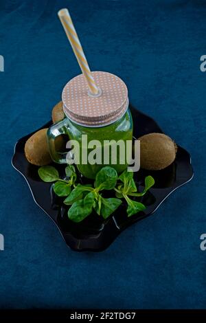 Smoothie aux feuilles de saladet au kiwi sur une assiette noire et décorée avec kiwi et laitue Banque D'Images